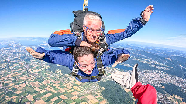 istock Tandem skydivers fly through air together, reach for hand 2230804770