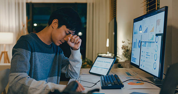 istock Young Asian man tired employee feeling mental burnout while working late at home office, overwhelmed by financial planning and data analysis tasks on multiple screens. Remotely and finance. 2230806057