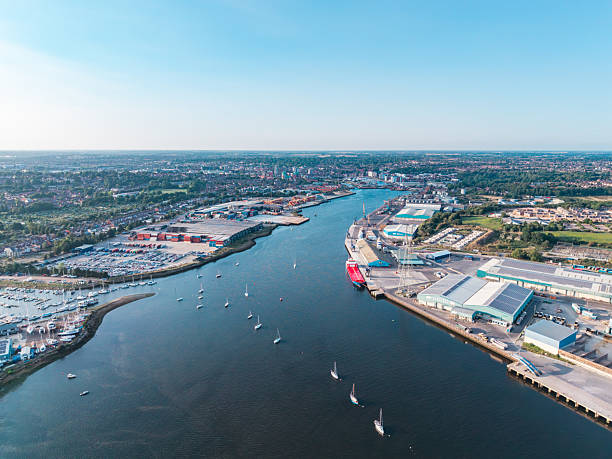 Drone view capturing the bustling ipswich waterfront, featuring the river orwell, industrial warehouses, and the cityscape under a clear sky