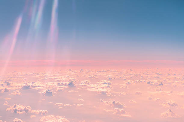 Sunlight streaming through fluffy clouds above creates a stunning interplay of pink and blue hues in the sky, evoking a dreamy, serene atmosphere filled with beauty and tranquility