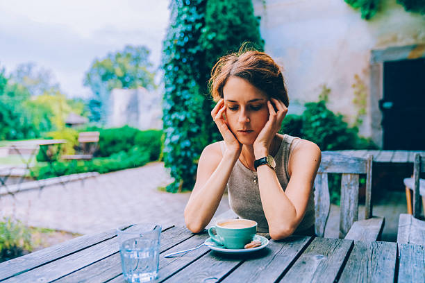 istock Woman sitting at outdoor cafe table feeling stressed 2230809639