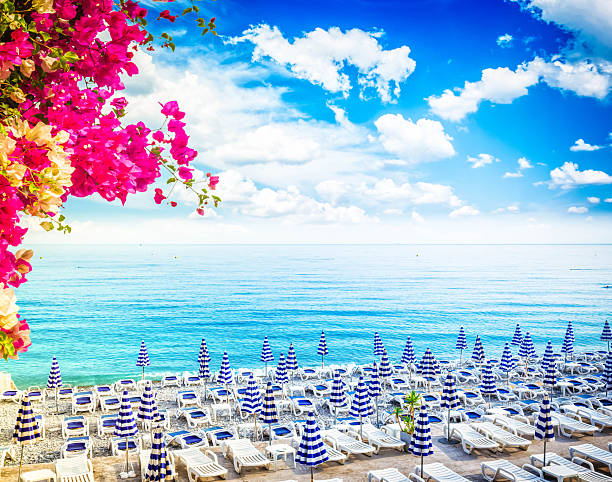Nice stone beach and turquiose calm water of cote dAzur at summer morning with flowers, France