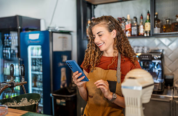 istock Smiling barista using smartphone behind counter 2230819192