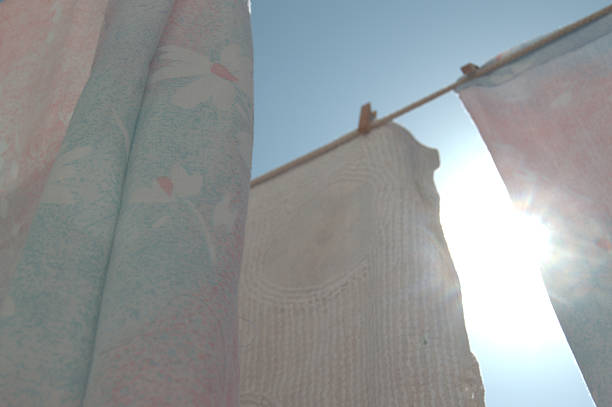 Fabric items hanging on a clothesline outdoors, with a clear blue sky in the background and natural sunlight. Concept of everyday life, cleanliness, freshness, and summer.