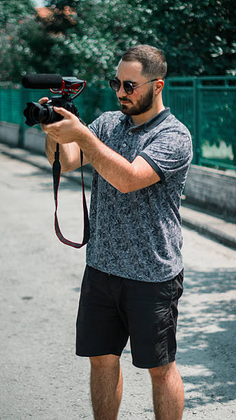 istock Man holding a photo camera and taking photos with it. Man using a video camera 2230838531