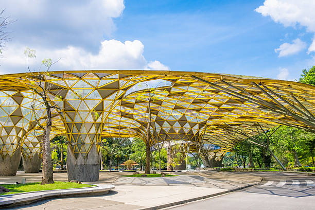 istock Perdana Botanical Garden, Kuala Lumpur, Malaysia with modern architectural structure with a yellow geometric roof and large open space surrounded by greenery and trees under a bright blue sky 2230839351