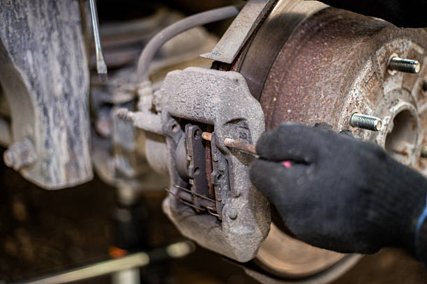 istock A mechanic removes the retaining elements of a brake caliper while replacing brake pads on a car 2230841005