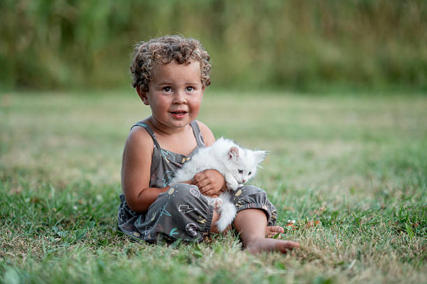 Preteen girl with cat on backyard lawn.