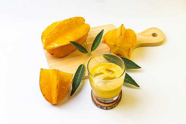 istock Golden star fruit and juice sit on a cutting board against a stark white background, fresh. 2230846670