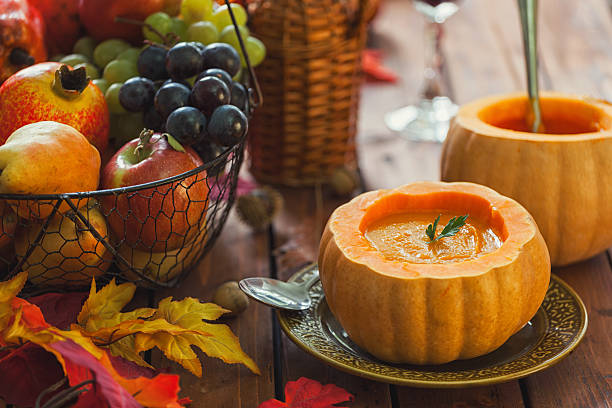 Homemade pumpkin soup on an old wooden table decorated with autumn leaves