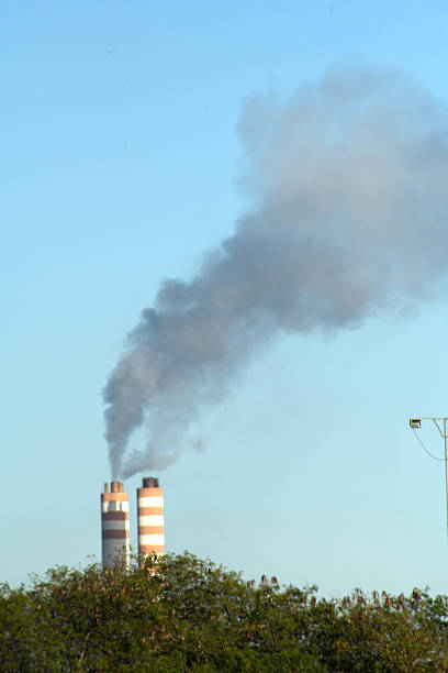 A powerful image of industrial chimneys emitting thick black smoke into the sky, highlighting the environmental impact of emissions. The dark smoke contrasts with the sky, creating a striking and impactful visual of pollution.