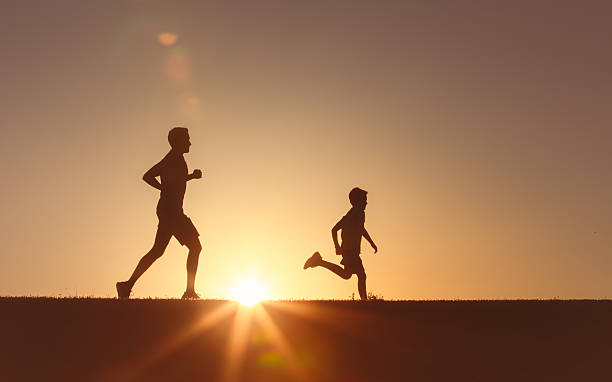 istock Father and son running together at sunset. 2230855075
