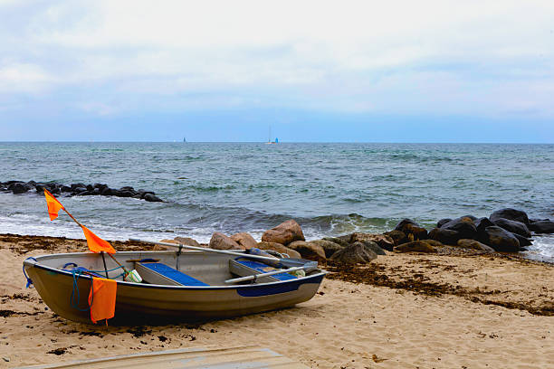 Lifeboats line the shore, waves crash gently, sky glows with light.