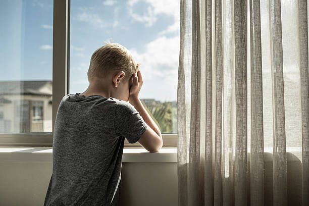 istock Sad unhappy lonely little boy at home crying next to window. 2230857338