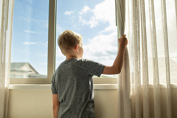 istock Thoughtful alone child at home looking out his window 2230857422