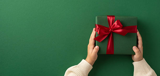 istock A hands holding a beautifully wrapped green gift box with a red bow on a green backdrop, evoking festive and celebratory emotions 2230861588