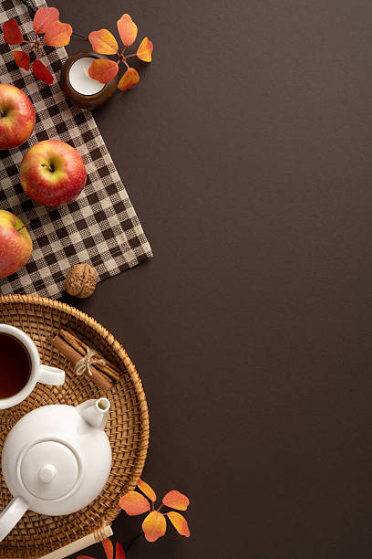 istock Warm vertical autumn aesthetic featuring a teapot, apples, and colorful leaves on a table 2230861607