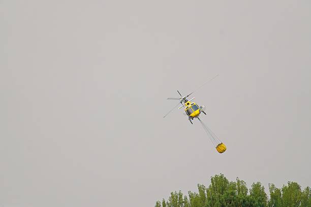 istock Firefighting helicopter carrying water while battling wildfire blaze spreading across forested landscape in leon, spain 2230863549