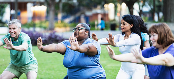 Multiracial group practicing tai chi in city park