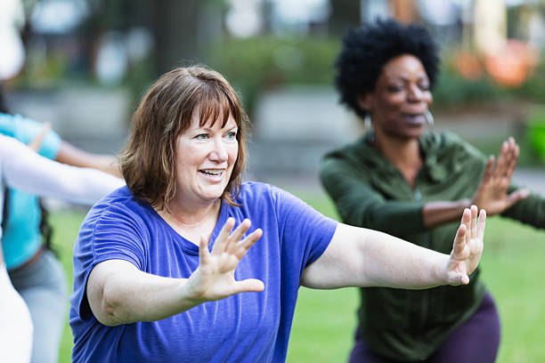 istock Mature woman practicing tai chi outdoors with group 2230863952