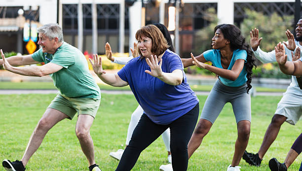 istock Mature woman practicing tai chi outdoors with group 2230863962