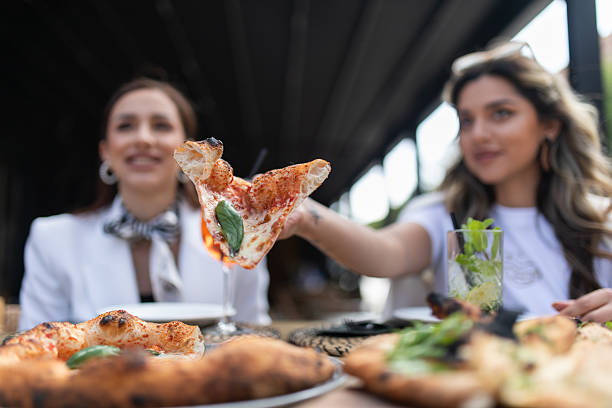 istock Friends Enjoying Fresh Pizza and Drinks Outdoors in a Stylish Cafe 2230865343