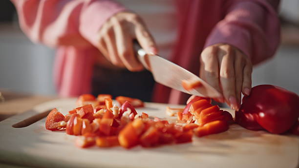 Unknown woman slicing vegetables chopping board kitchen closeup. Hands cutting