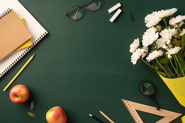 istock Stationery items, fresh apples, and white flowers arranged on a teacher-themed classroom setup 2230868717