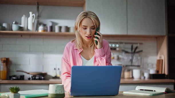 istock Multitasking freelancer talking smartphone typing laptop at kitchen closeup 2230869654