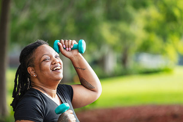 istock Black woman at park exercises with dumbbell hand weights 2230879135