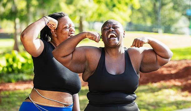 istock Two black women exercising, flexing biceps outdoors 2230879163