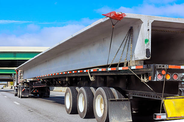 istock Construction vehicle transporting large concrete beam on highway during daylight hours in urban area 2230881546