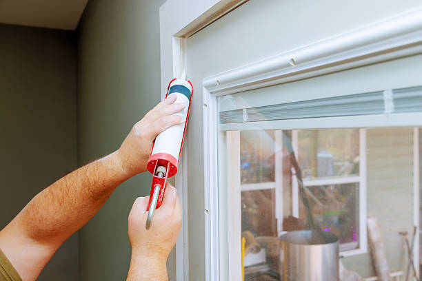 Home renovation project with person applying caulk around window frame in well lit indoor setting