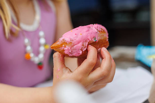 istock Child Holding Pink Frosted Donut with Sprinkles 2230884391