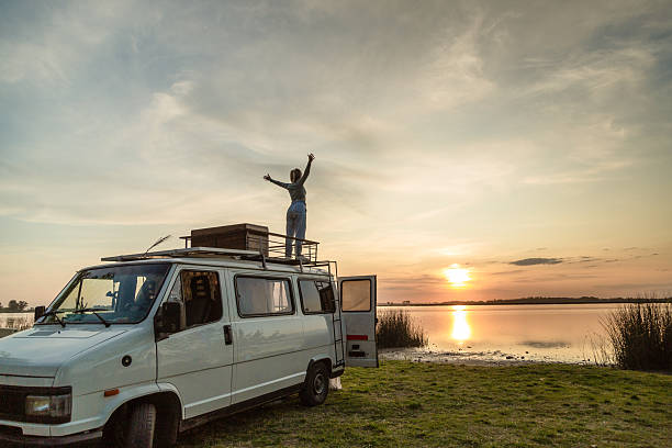 Young woman on a motorhome in nature watching the sunset