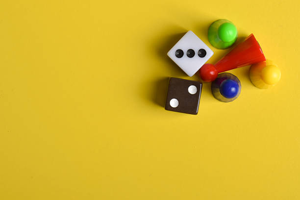 Colorful board game figures and dice isolated on yellow background, top view