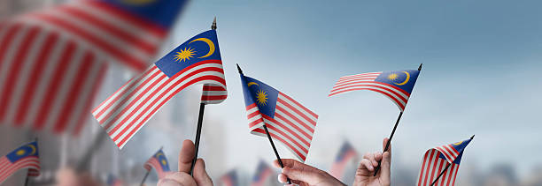 istock Malaysia flags in their hands on a blurred urban background 2230895655