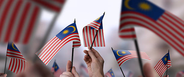 istock Malaysia flags in their hands on a blurred urban background 2230895660