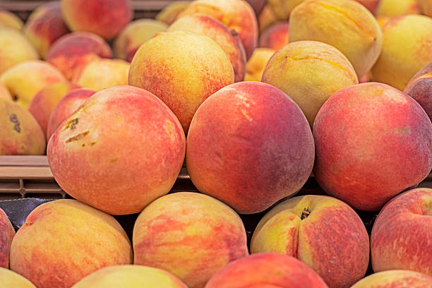 Baskets of fresh peaches with green leaves for sale at a farmer's market