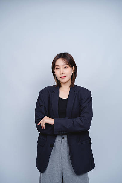 istock Confident Woman in Blazer Posing Against a Gray Background with an Engaging Expression and Stylish Outfit, Perfect for Business or Fashion Themes 2230902619