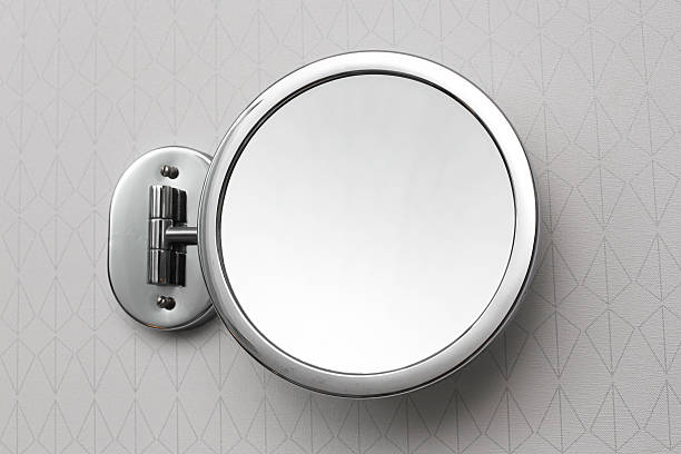 istock Wall mounted round bathroom mirror. Chrome framed cosmetic mirror attached to tiled wall. 2230902891