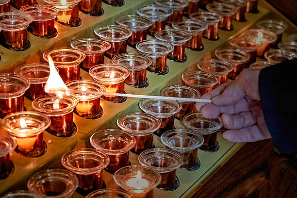 istock Candles burning in a church with hand visible lighting a candle 2230904932