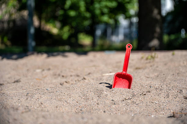 A bright green shovel and a mint bucket sit on a red and green playground surface, capturing a playful outdoor scene perfect for kids, family, and summertime fun.