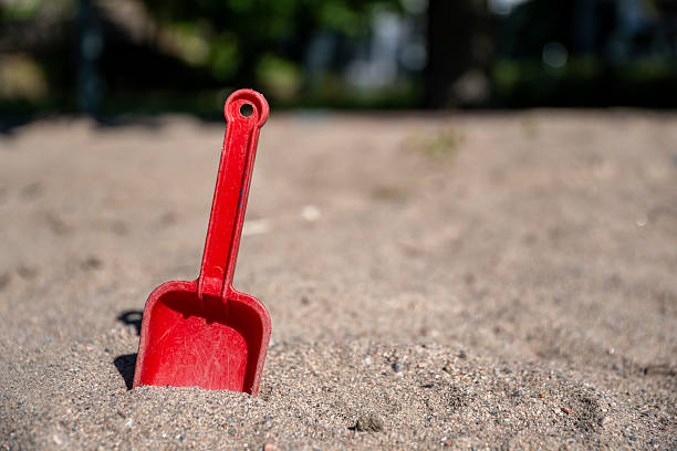 Bright Red Toy Shovel Stuck in Sandbox Dirt