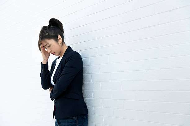 istock Woman holding her head against a white wall 2230910939