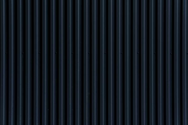 istock Vertical ridges and grooves define a dark corrugated metal wall 2230911472