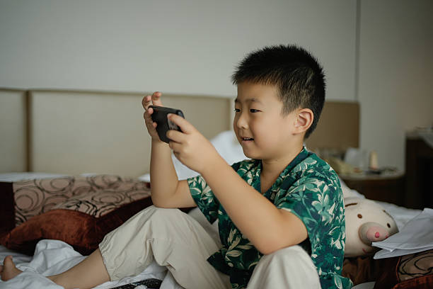 istock A little boy sitting on the bed playing a video game 2230912932