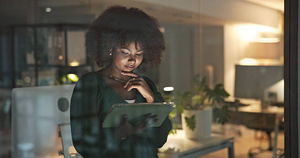 istock Focused Businesswoman Using a Tablet Late at Night in an Office Setting 2230913232