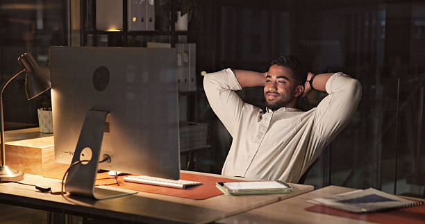 Businessman Relaxing at Workplace in a Modern Office at Night