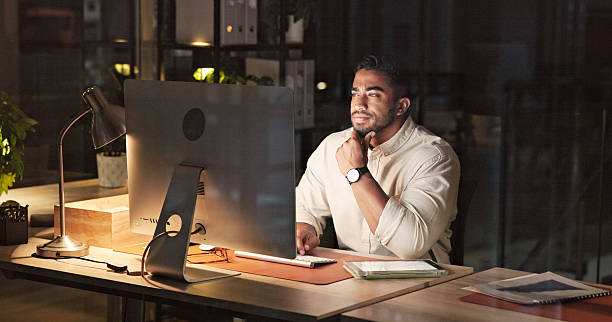istock Focused Businessman Working Late at Office Desk in Dimly Lit Environment 2230913247